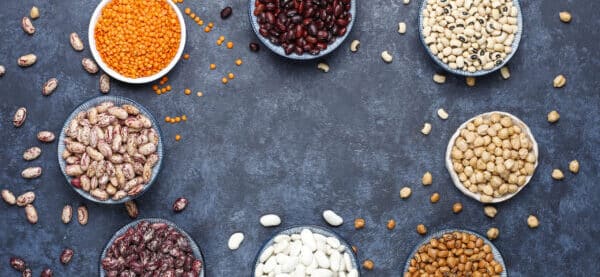 Legumes and beans assortment in different bowls on light stone b